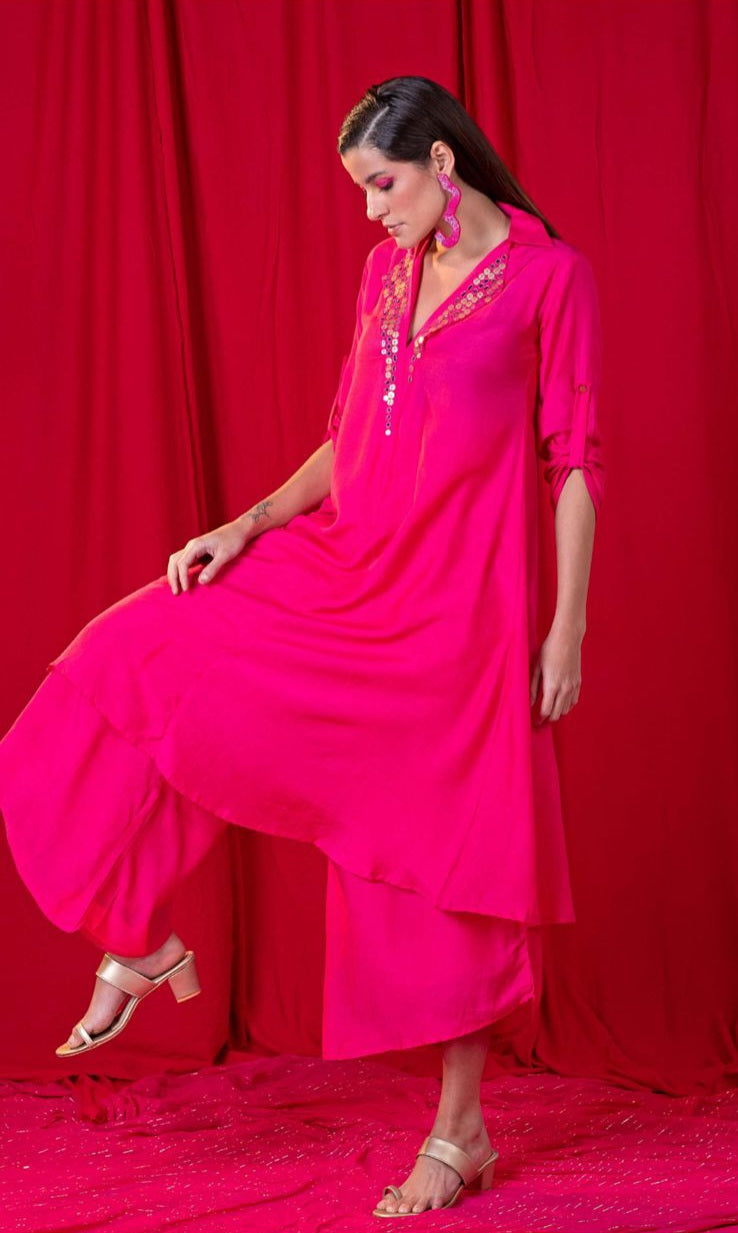 Image of This stunning twin set is made from high-quality fabric and features an embellished V-neckline with metallic and mirror embroidery, paired with an asymmetric palazzo pant. Perfect for a special occasion, the pink design exudes elegance and sophistication.  From savoirfashions.com