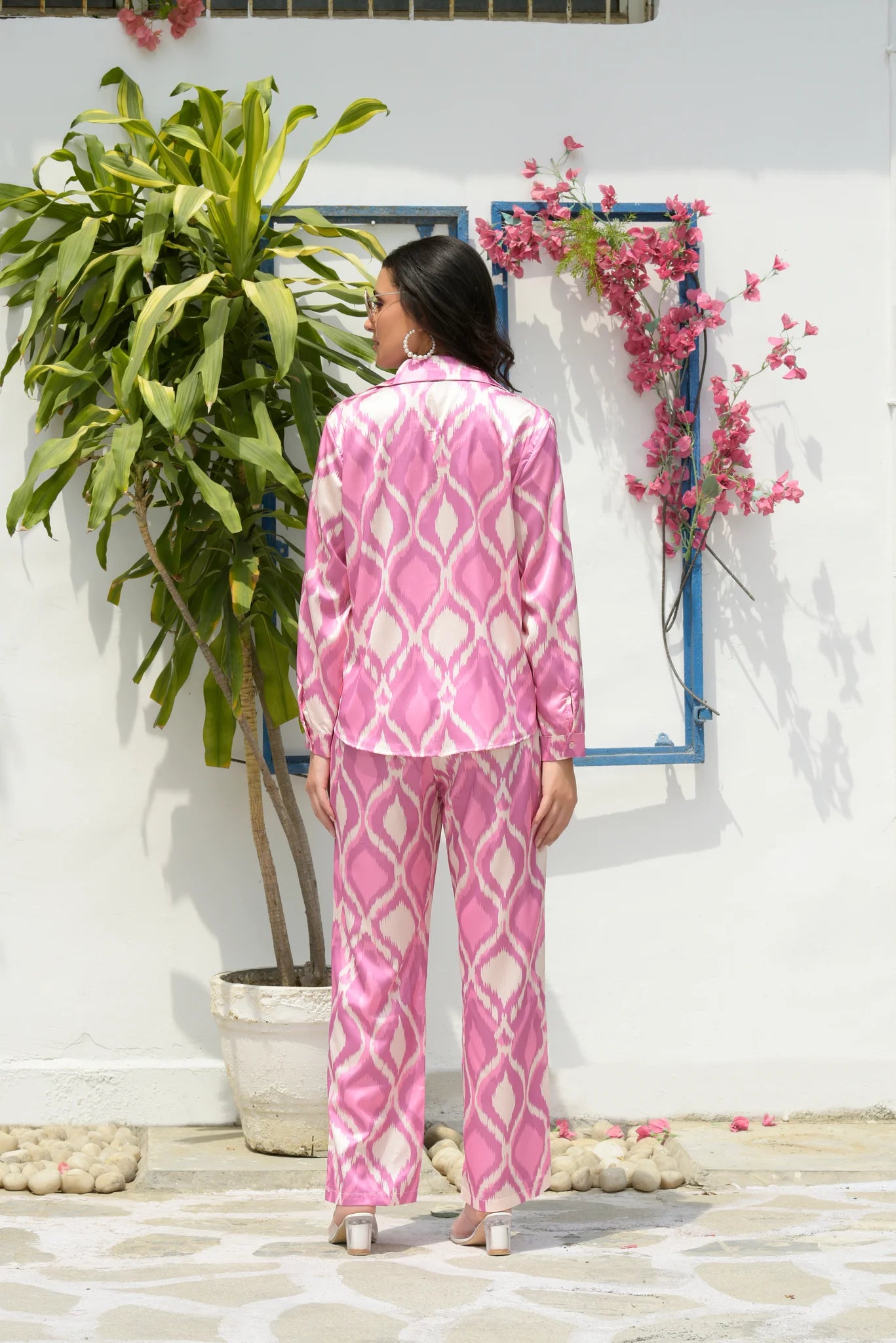 Image of This SICILEY SATIN IKAT CO-ORD SET in Pink Plush is perfect for any occasion. Its detailed ikat pattern is crafted from 100% satin material for a luxurious feel. The set includes a classic-fit shirt and straight-fit pants for a stylish, co-ord look. From savoirfashions.com
